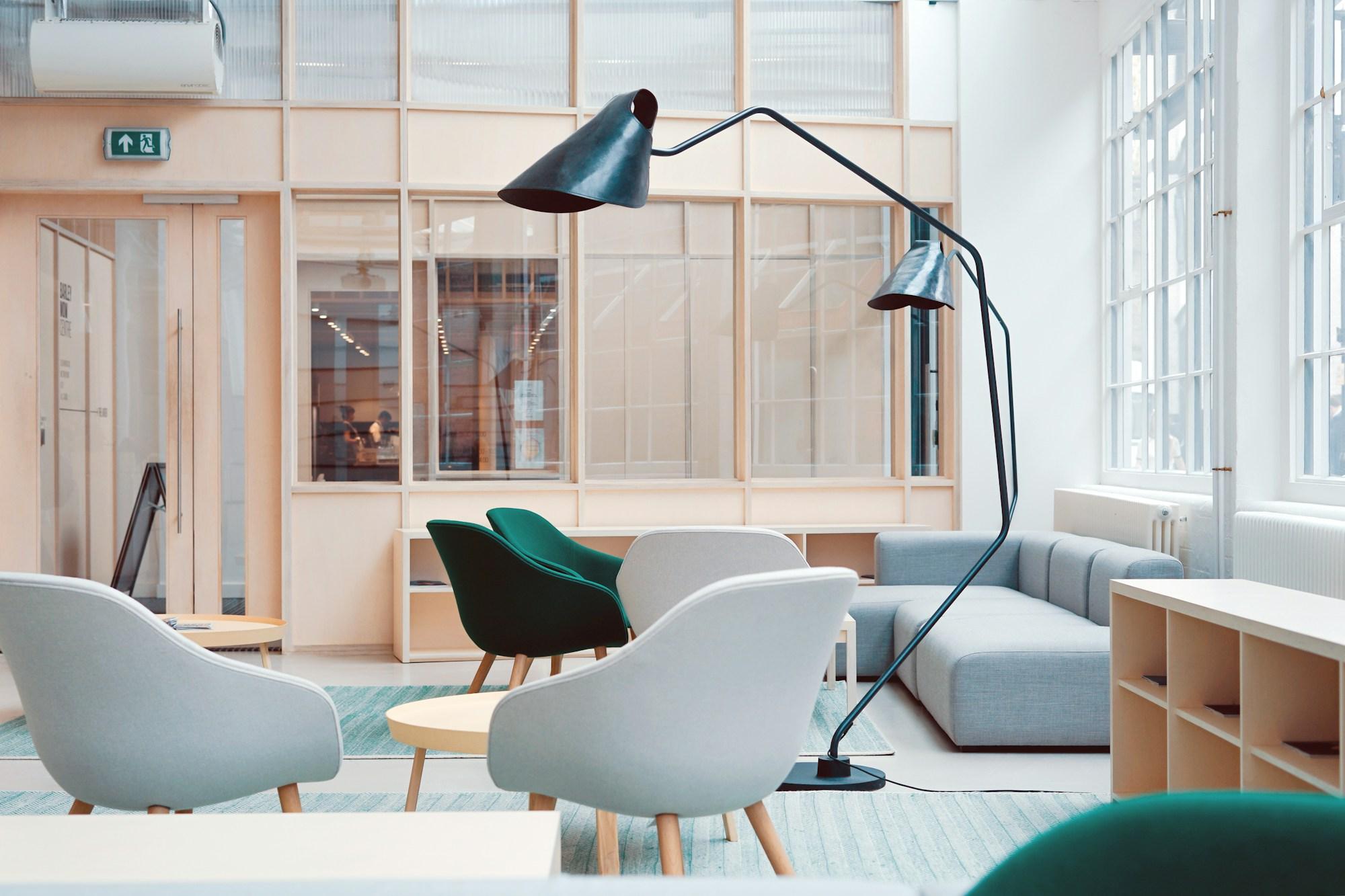 A light-filled creative meeting space with green seating and large black task lights